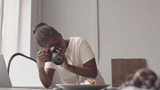 Medium slowmo shot of Black female photographer taking photos of breakfast at table on professional camera - Filmagem, Vídeo