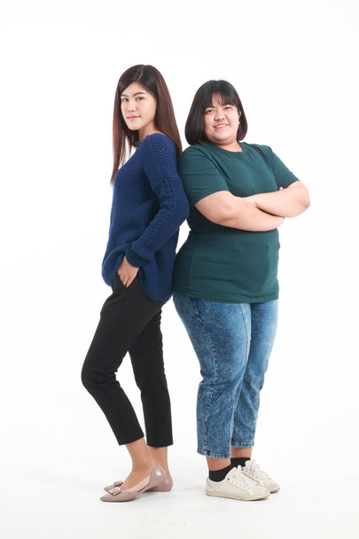 Portrait. Two fat and skinny Asian women. standing on a white background Happy smile. The concept of health care to lose weight. - Fotó, kép
