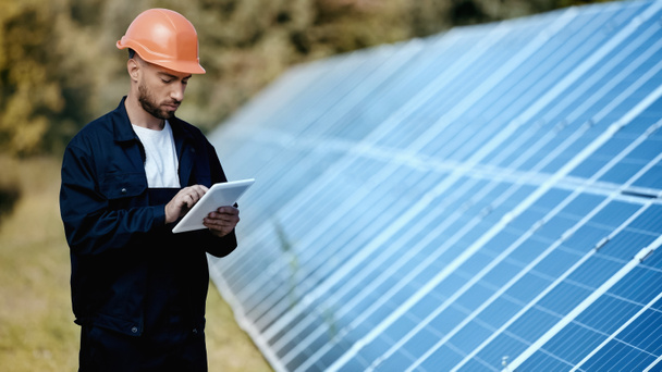 engineer using gadget while standing near solar panel  - Φωτογραφία, εικόνα