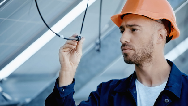 engineer in hardhat checking wire of solar panel - Fotoğraf, Görsel