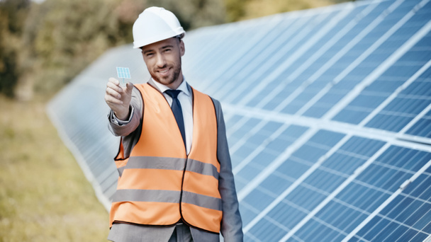 cheerful businessman showing small solar battery model - Photo, Image
