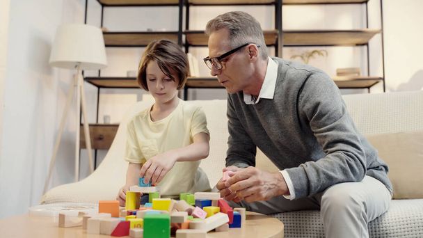 middle aged grandfather playing building blocks with preteen grandchild  - Valokuva, kuva