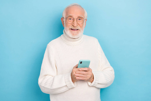 Portrait of attractive cheery skilled grey-haired man using device gadget media smm app isolated over bright blue color background - Φωτογραφία, εικόνα