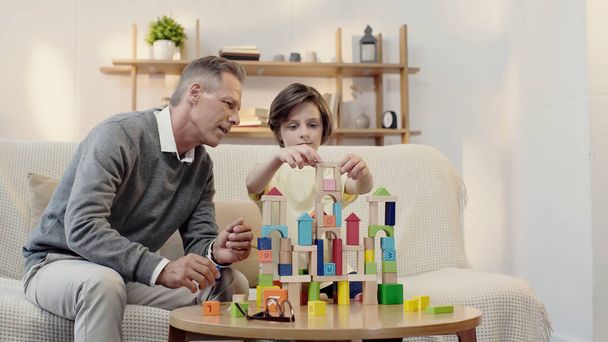 middle aged grandfather playing building blocks with preteen boy - Fotografie, Obrázek
