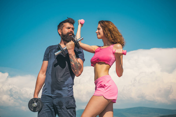 Sportive woman and man, team. Sport, dumbbell and fitness, couple sports. Sporty sexy couple showing workout wiht dumbbells. Sports fitness girl. Active couple exercising outdoors. - Foto, Imagen