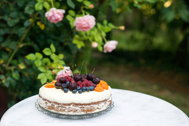 fruit cake for a garden party against the backdrop of blooming roses - selective focus, copy space - Fotoğraf, Görsel
