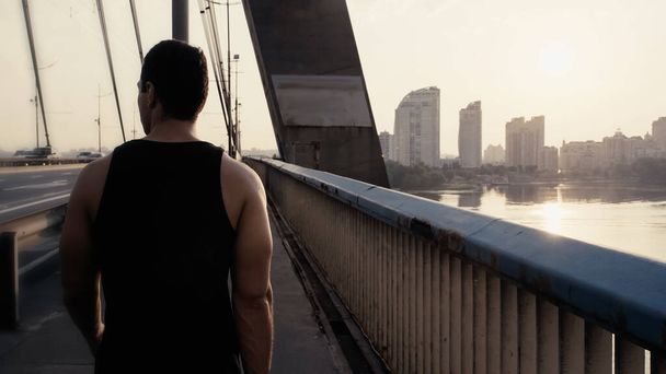 vista posteriore dello sportivo mista uomo corsa a piedi sul ponte della città - Foto, immagini