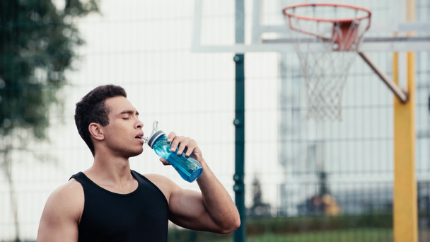 deportista de carrera mixta con los ojos cerrados beber agua de la botella de deportes al aire libre - Foto, Imagen