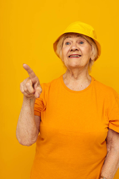 Photo of retired old lady in yellow t-shirts hat posing isolated background - Fotó, kép