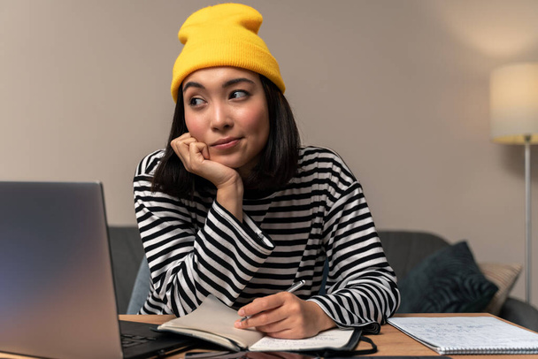 Набридла незадоволена азіатка, що носить жовтий капелюх, намагаючись зрозуміти онлайн-курс освіти вдома. Стокова фотографія
 - Фото, зображення