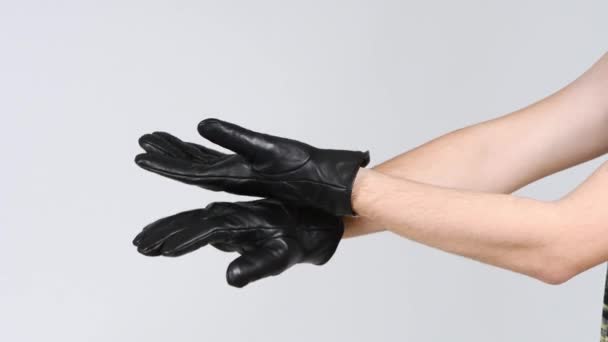 Un homme portant des gants noirs claque des mains avec le dos de sa main. Vue latérale. Vidéo 4K UHD 3840X2160. - Séquence, vidéo