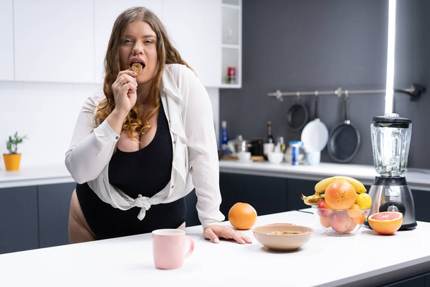 Sexy Woman Plus Size in Black Bodysuit and White Shirt has a Snack in the Kitchen. Healthy Food, Breakfast, Fruits, Citrus Fruits. Body Positive. Close-up - Fotoğraf, Görsel