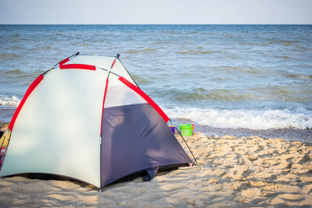 une tente grise et rouge se dresse sur le bord de la mer, plage sauvage, repos, randonnée, hébergement, mer, vacances - Photo, image