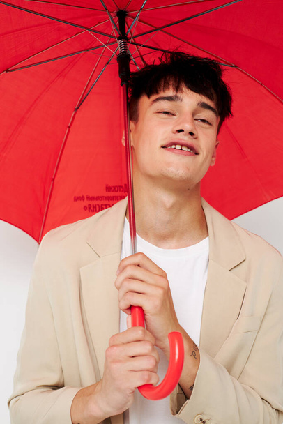 Мужчина, держащий зонтик в руках позирующего модного светлого фона без изменений - Фото, изображение