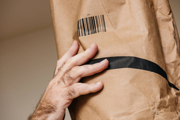Άνδρας χέρι στο κεφάλι καλύπτεται με Amazon Prime χάρτινο φάκελο - Φωτογραφία, εικόνα