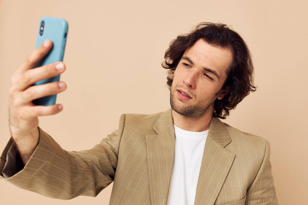 Ελκυστικός άντρας με κοστούμι που δείχνει συναισθήματα κοιτάζοντας το τηλέφωνο απομονωμένο φόντο - Φωτογραφία, εικόνα