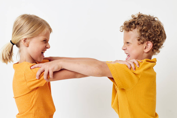 Small children in yellow t-shirts standing side by side childhood emotions light background unaltered - Foto, immagini