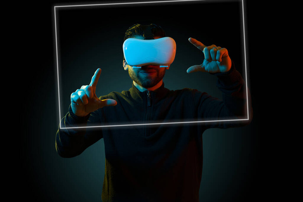 Happy latin man using a virtual realty headset and enjoying the new futurist technology while on the metaverse - Foto, afbeelding