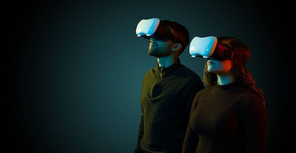 Young couple looking up and experiencing the metaverse together with high tech virtual reality glasses - Fotografie, Obrázek