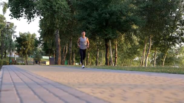 outdoor exercise of sporty man running in park, sprinting - Filmati, video