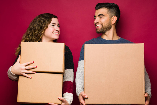 Beautiful woman moving in with her boyfriend while carrying boxes. Happy couple moving to a new house or apartment  - Foto, imagen
