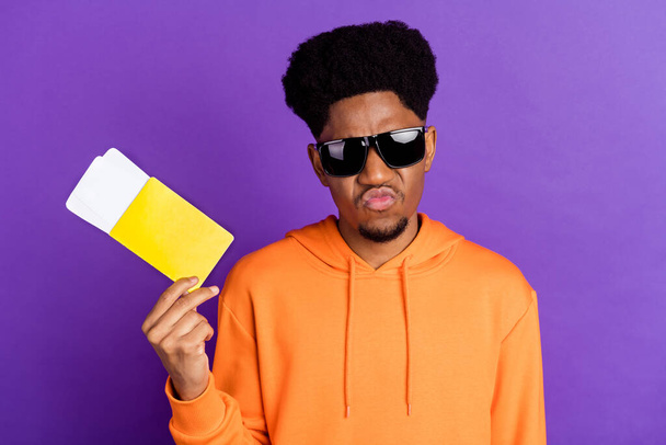Photo of cool brunet millennial guy hold tickets wear spectacles orange sportswear isolated on purple color background - Fotoğraf, Görsel