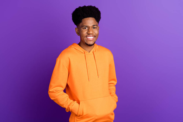 Photo of happy young dark skin man hold hands orange hoodie smile street style isolated on purple color background - 写真・画像