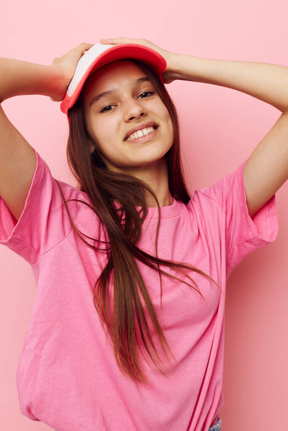 cheerful young girl with a cap on her head in a pink t-shirt - 写真・画像