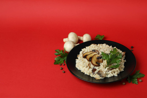 Concept of tasty food with risotto with mushrooms on red background - Фото, зображення