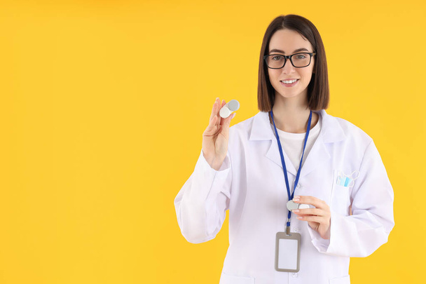 Female trainee doctor with lenses on yellow background - Photo, image