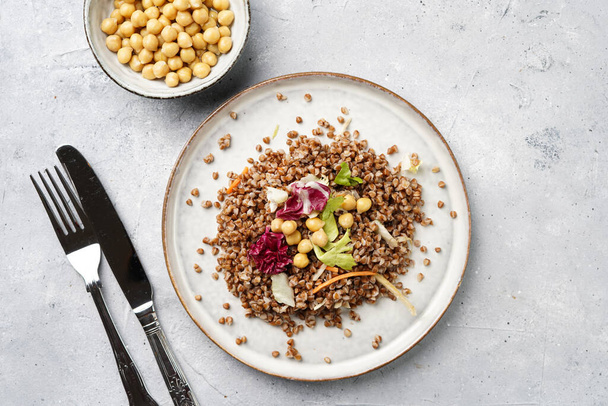 grey porcelain scandi plate with traditional east european dish buckwheat salad with butter and chickpeas on concrete surface, top view - Photo, Image