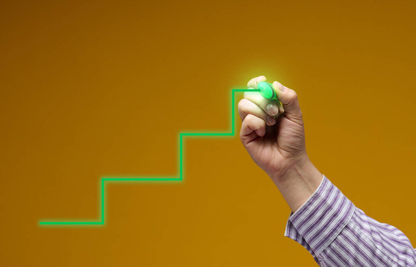 grüne Schritte, die von einer Hand auf gelbem Hintergrund gezeichnet wurden. Karrierewachstum, persönliches Wachstum, Unternehmensgründung - Foto, Bild