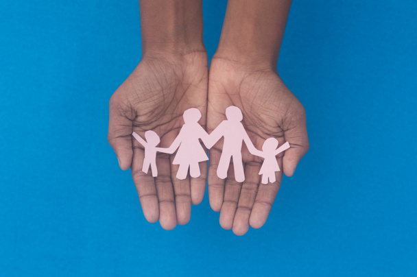 Ręczne trzymanie rodzinnej sylwetki na górze. Światowy Dzień Zdrowia Ochrona przed przemocą domową, opieką zdrowotną i przeszłością medyczną. Opieka zastępcza, wsparcie bezdomnych i koncepcja dystansu społecznego. - Zdjęcie, obraz