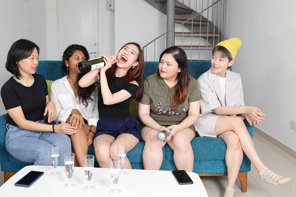 Νεαρή ασιατική ομάδα γυναίκα μιλάμε κουτσομπολιά τραγουδούν ποτό ζητωκραυγές διασκέδαση κόμμα Απολαύστε μεθυσμένος κουρασμένος ξεκούραση αστεία πρόσωπα έκφραση στο μπλε σαλόνι καναπέ μπουκάλι - Φωτογραφία, εικόνα