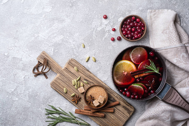 Autumn or christmas traditional drink with oranges, cranberry, cinnamon, rosemary and other ingredients on grey concrete background - Fotoğraf, Görsel
