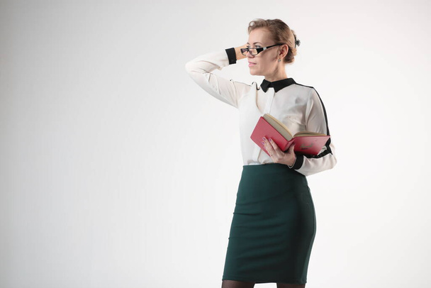 the teacher is a woman with glasses and a book in her hand - Foto, afbeelding