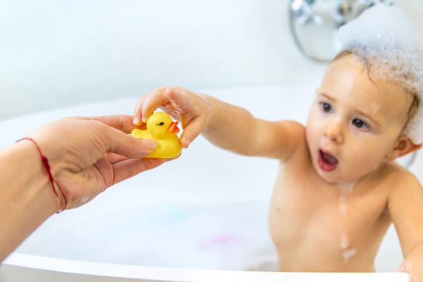 Uma criança toma banho em um banho de espuma. Foco seletivo. Feliz.. - Foto, Imagem