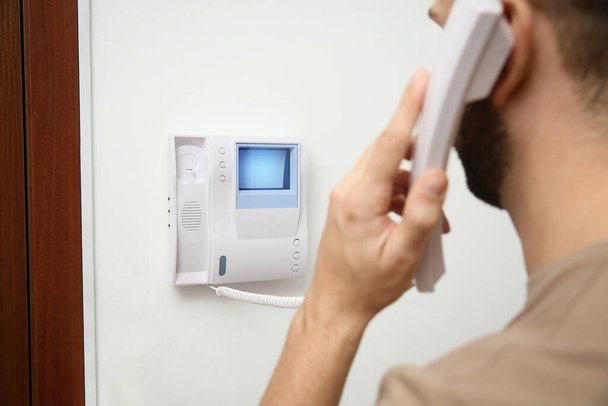 Man with handset answering intercom call indoors - Photo, Image