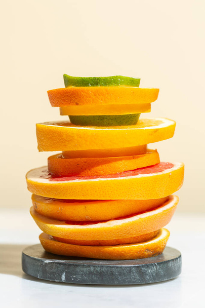 Slices of citrus fruits are stacked on a stone stand, fruit cocktail, fresh juice - Фото, изображение