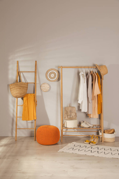 Modern dressing room interior with stylish clothes, shoes and orange pouf - Valokuva, kuva