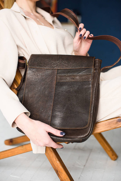 close-up photo of brown messanger leather bag in womans hands - Фото, изображение