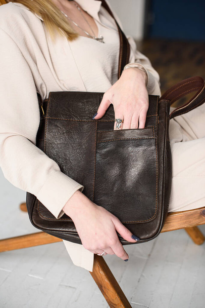 close-up photo of brown messanger leather bag in womans hands - Fotó, kép