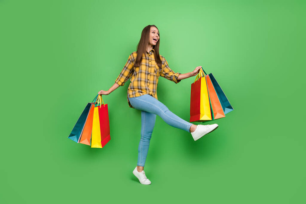 Full size portrait of carefree shopper lady look empty space have good mood isolated on green color background - Fotoğraf, Görsel