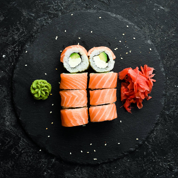 Sushi rolls with salmon. Traditional Japanese food. On a black stone plate. - Fotografie, Obrázek