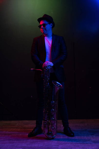 Saxophonist Guy Standing with Tenor Saxophone, Musician Blows the Saxophone. Neon Light - Zdjęcie, obraz