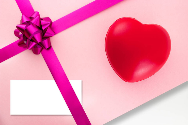 Corazón rojo y tarjeta de felicitación blanca vacía para texto sobre regalo rosa con cinta púrpura y lazo. Antecedentes para San Valentín o Cumpleaños. Vista superior. - Foto, Imagen