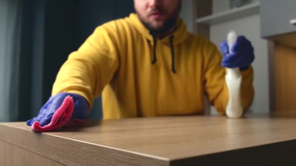 Brodaty pracownik domu sprząta dom za pomocą chusteczki i sprayu do dezynfekcji podczas noszenia rękawiczek - Materiał filmowy, wideo
