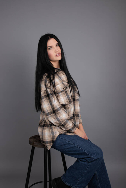 portrait of beautiful young woman in brown checkered shirt and jeans on gray background. pretty female portrait - Fotografie, Obrázek