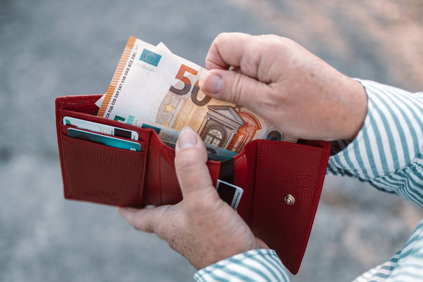 50ユーロ紙幣で赤い革の財布を保持するビジネス女性の手の閉鎖 - 写真・画像