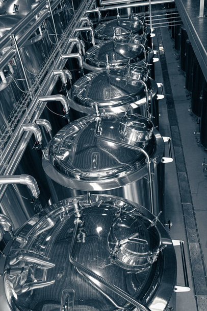 Ανοξείδωτοι σωλήνες στο εργοστάσιο. Ιδιωτική μικροζυθοποιία. Σύγχρονο εργοστάσιο μπύρας με βραστήρες, σωλήνες και δεξαμενές από ανοξείδωτο χάλυβα - Φωτογραφία, εικόνα